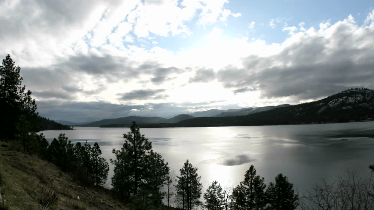 la brillante luz del sol atraviesa las nubes de tormenta que pasan sobre un lago de idaho
