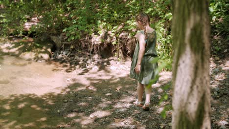 young girl watching a butterfly fly in a woodland near a pond