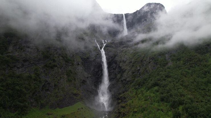 Cascata epica tra le nuvole, ripresa drone con zoom indietro, doppia cascata di Mardalsfossen in Norvegia