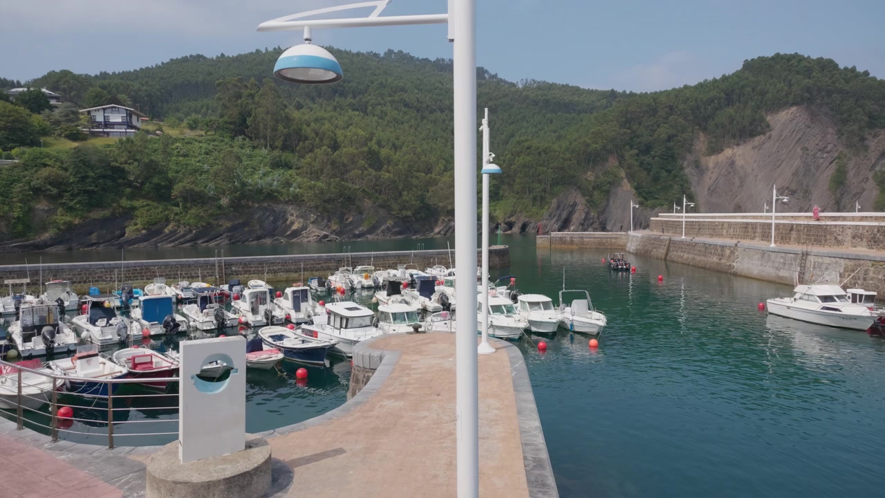 Porto de pesca de Armintza no País Basco, Espanha, com inúmeros pequenos barcos atracados, refletindo o estilo de vida costeiro e a economia marítima