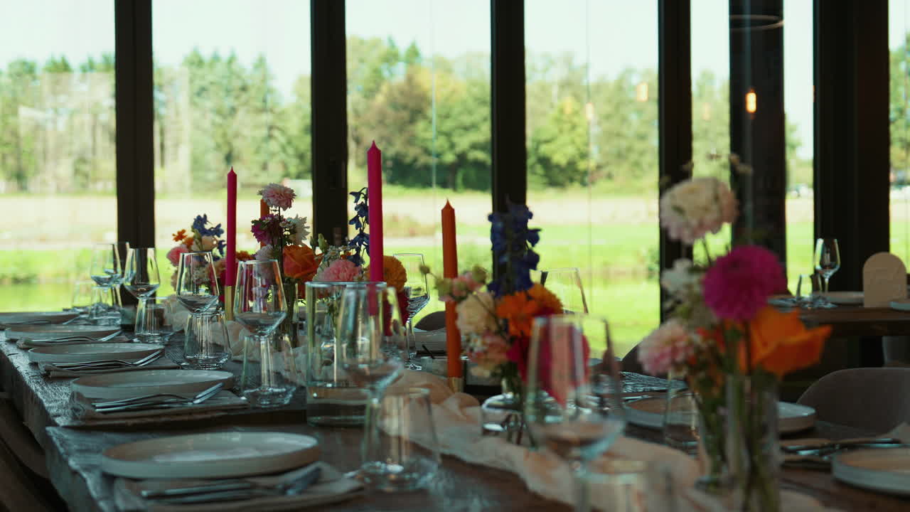 Close view of decorated wedding tables featuring flowers, invitation cards, cutlery, and natural greenery outside, creating a refined and festive atmosphere
