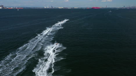 aerial-chase-of-a-group-of-jet-ski-riders-on-the-waters-between-Brooklyn---Staten-Island,-New-York,-moving-towards-New-York-City-and-the-horizon
