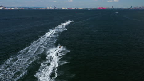 aerial chase of a group of jet ski riders on the waters between brooklyn - staten island, new york, moving towards new york city and the horizon