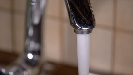 Pouring-tap-water-from-a-faucet-in-home-kitchens-sink-slow-motion-close-up