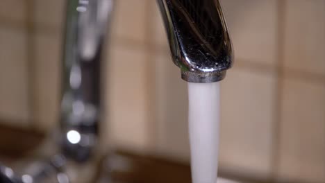 pouring tap water from a faucet in home kitchens sink slow motion close up