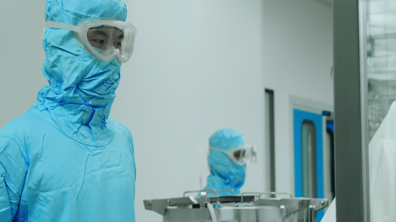 Scientist or sterile pharmaceutical production cleanroom features gleaming stainless steel equipment, Worker wearing protective uniform works on industrial machinery amidst advanced biopharmaceutical