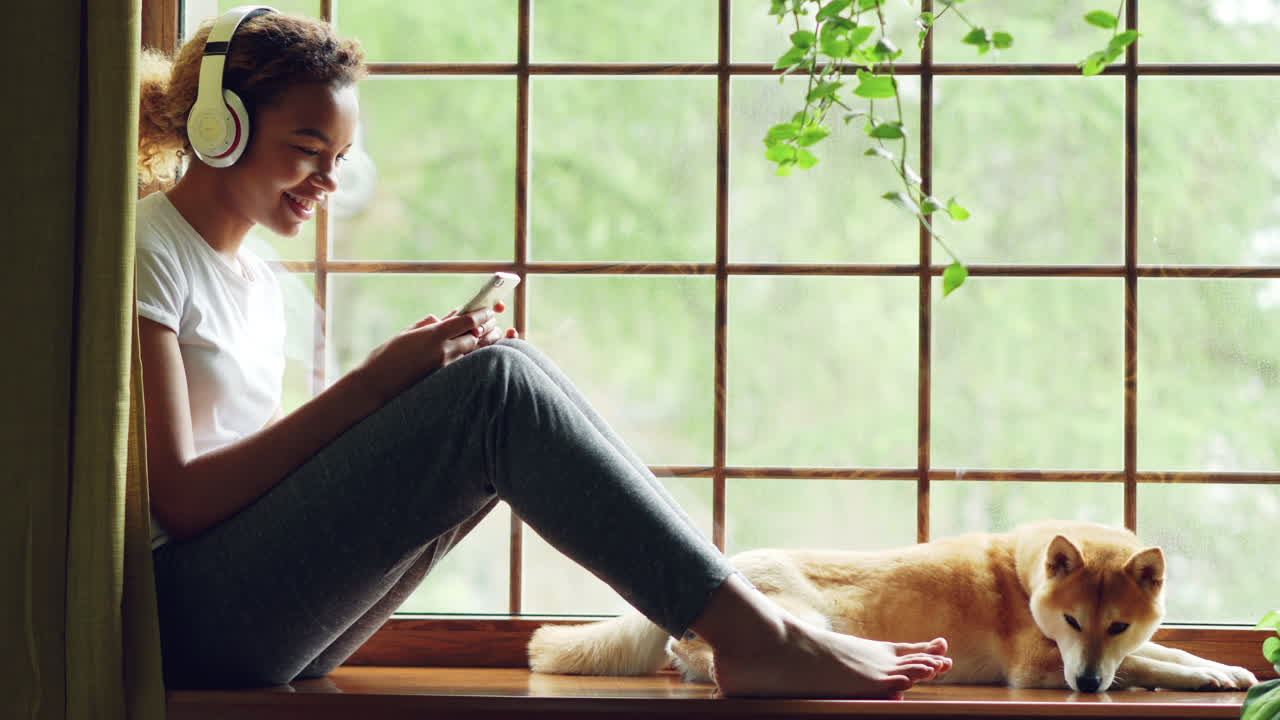 Teenage Girl Relaxing at a Window with Headphones and Dog