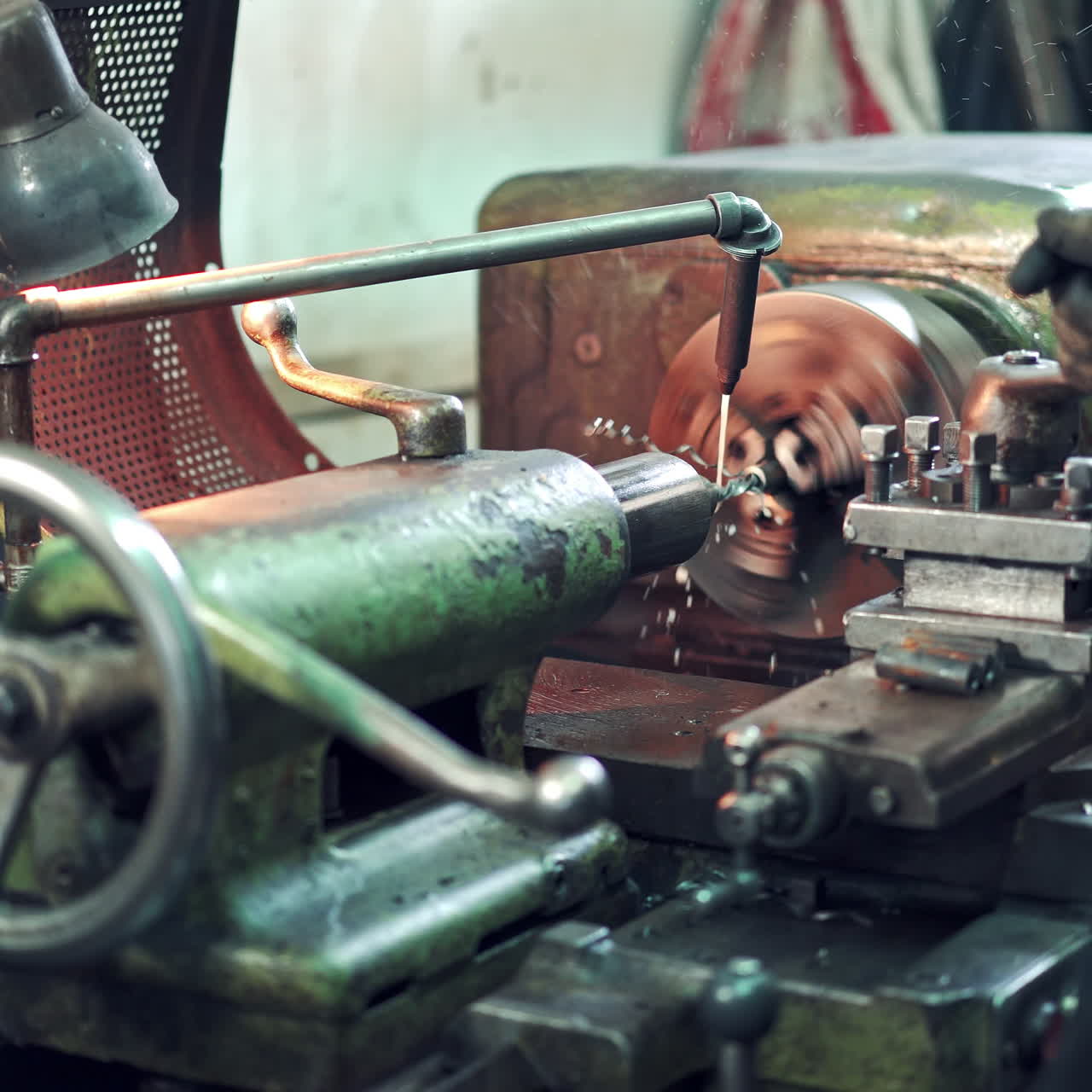 A worker controls the process of drilling a hole in a part on a lathe using coolant for cleanliness processing of surface. Close-up.