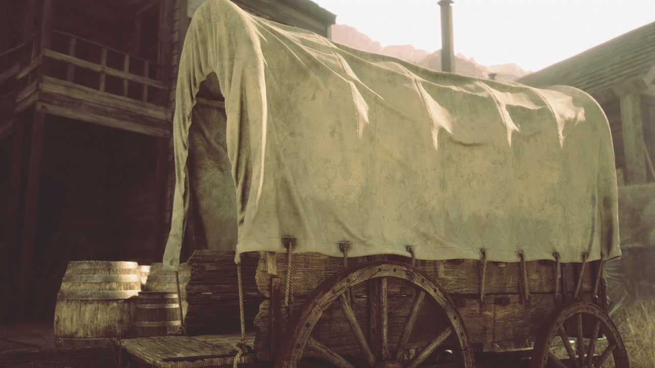 Old covered wagon parked near wooden barrels in a rustic setting