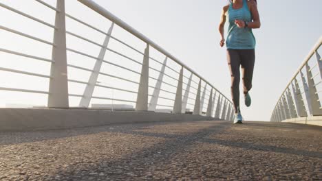 mujer joven corriendo por un puente