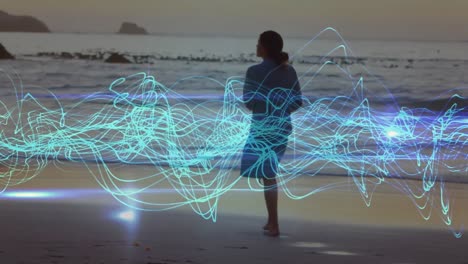 animation of blue lines over caucasian woman walking on beach