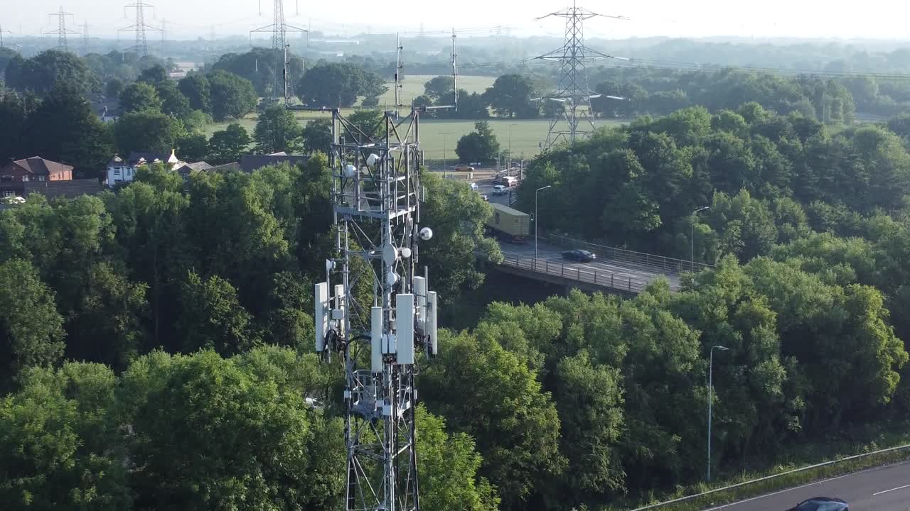 antena de torre de transmisión 5g en el campo británico con vehículos que viajan en el fondo de la carretera