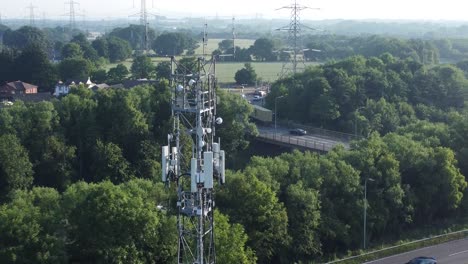 5g broadcasting tower antenna in british countryside with vehicles travelling on highway background