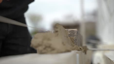 worker with trowel placing cement for laying brick wall at construction site