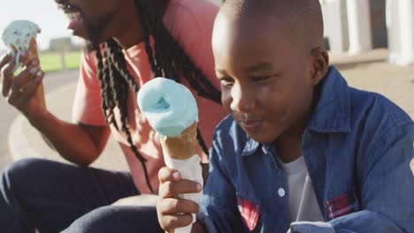 Video-Eines-Glücklichen-Afroamerikanischen-Vaters-Und-Sohnes,-Der-An-Einem-Sonnigen-Tag-Eis-Isst