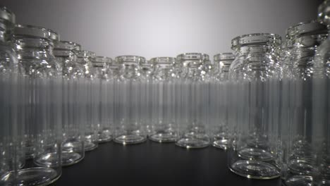 rows of clear empty glass vials arranged on a dark surface