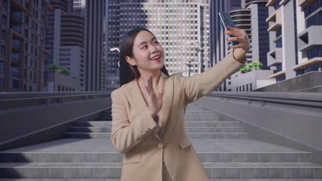 아시아 사업가 여성이 도시 거리에서 스마트 폰을 통해 누군가와 비디오 컨퍼런스 통화를 하고 있습니다.