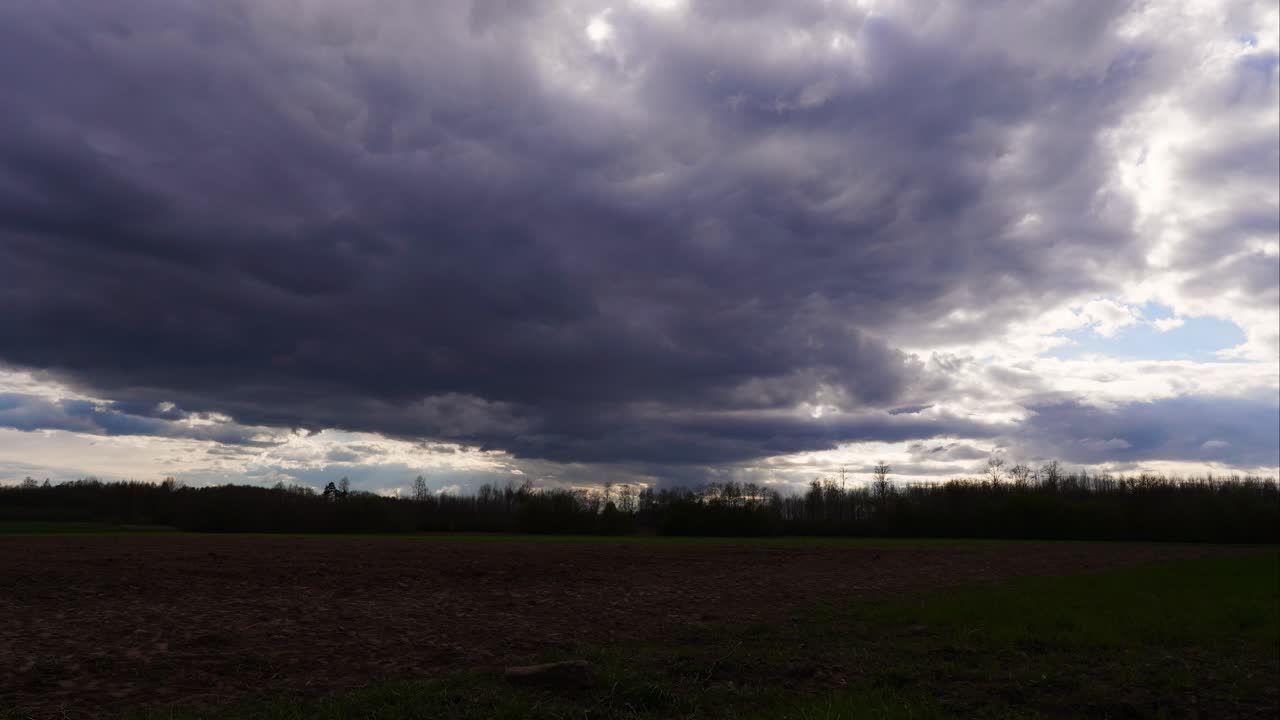 Dramatisk timelapse af regnskydannelse over mørkt landbrugsland, solen kommer frem.