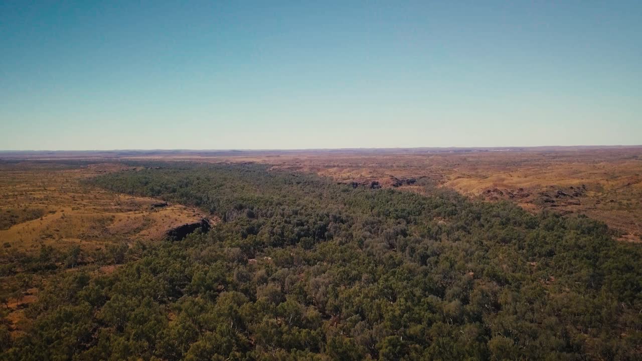 Letecký pohled z dronu z ptačí perspektivy s pomalým náklonem vzhůru přes vnitrozemskou řeku v australské pouštní oáze