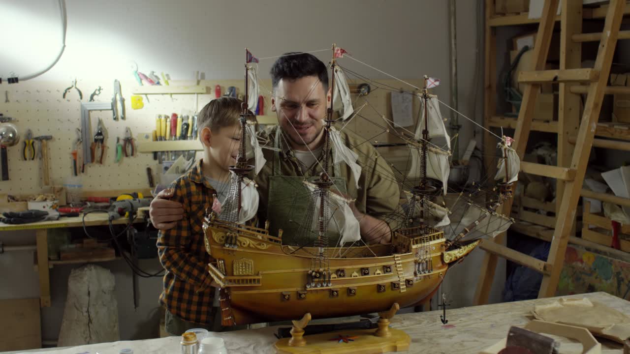 행복 한 아버지 와 아들 이 배 모델 을 보고 있다