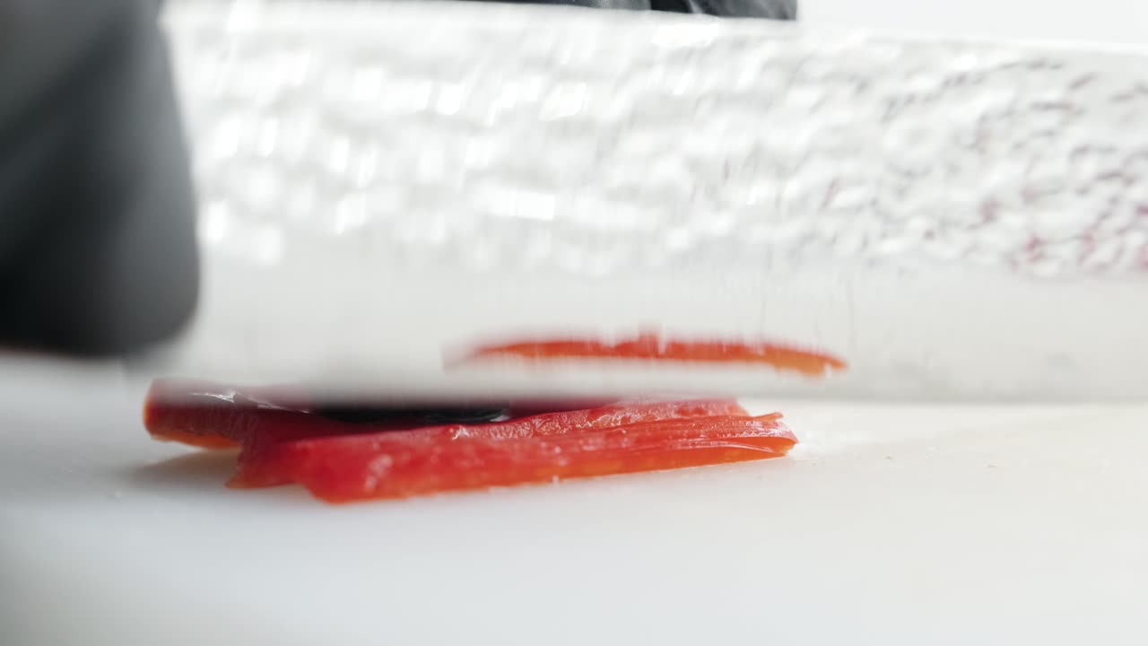 el cocinero corta la pimienta roja con un hermoso cuchillo