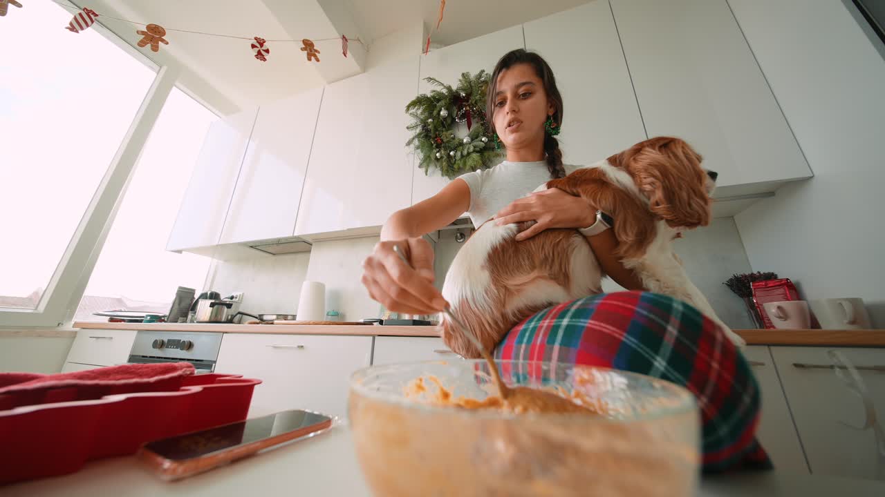 Woman Baking with Dog in Kitchen at Christmas