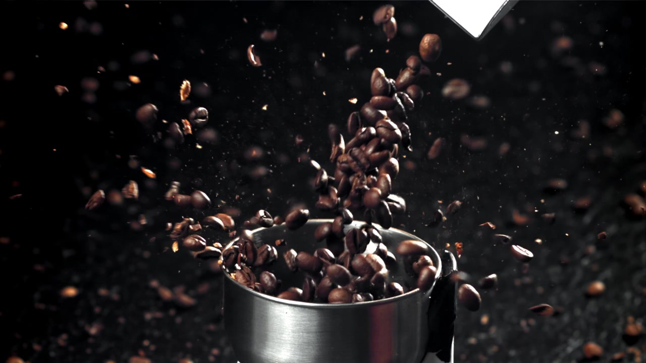 Chicchi di caffè tostati che si versano in un macinacaffè al rallentatore
