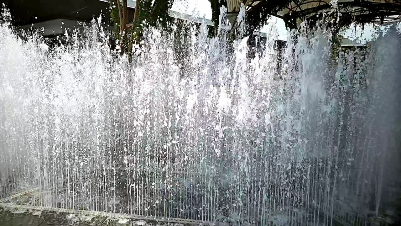 Slow motion shot of the rhytmic rising and falling of a fountain in the middle of a local community mall in Bangkok, Thailand