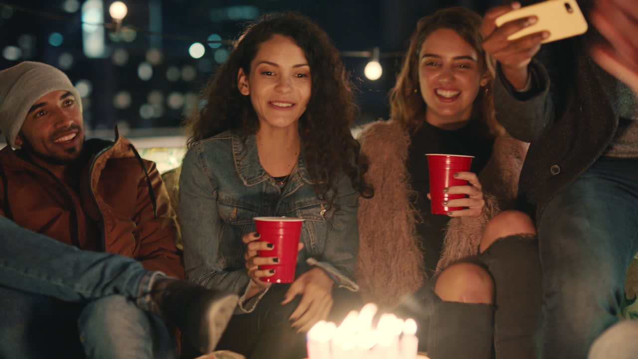 grupo de amigos multirraciales celebrando una fiesta de cumpleaños en la azotea por la noche hermosa joven soplando velas disfrutando de la amistad divirtiéndose compartiendo la celebración