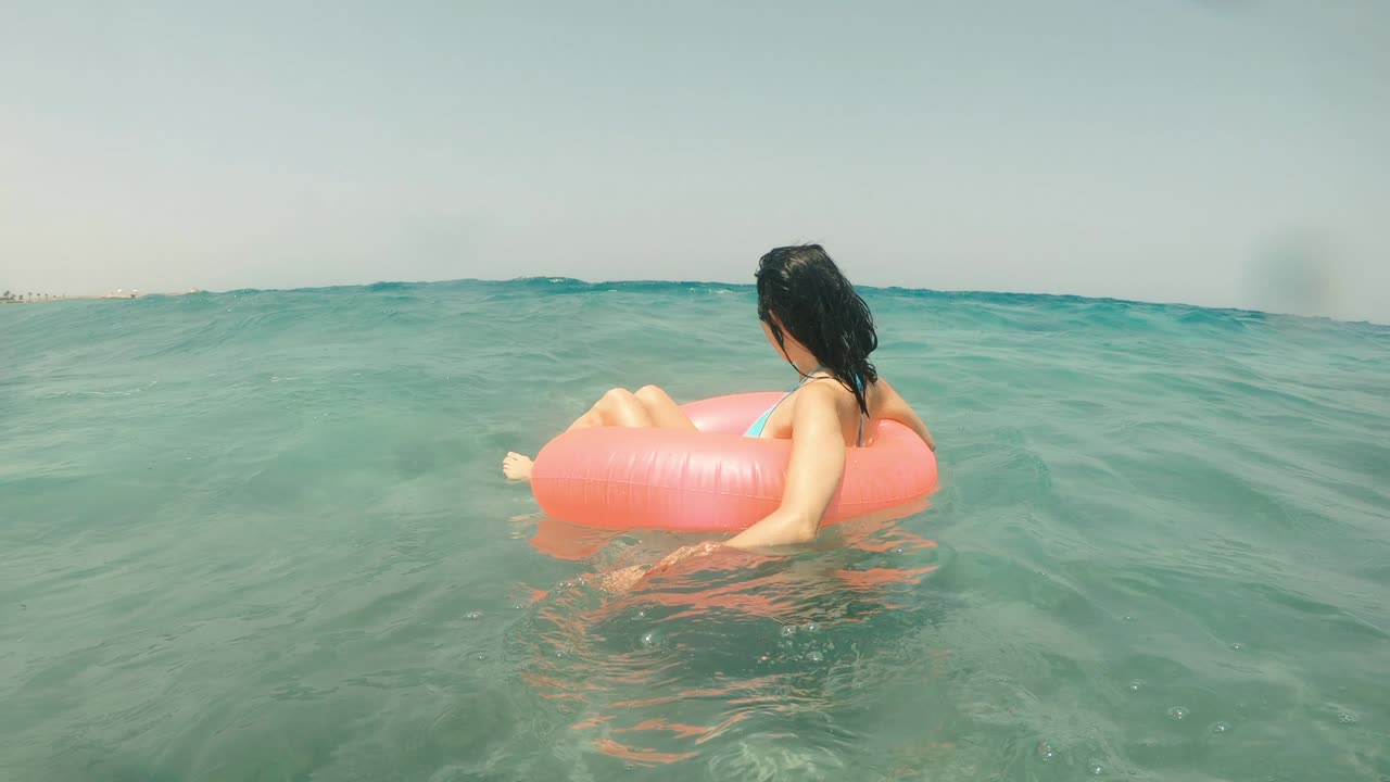 Sea wave. Woman swims on an inflatable ring in the sea.