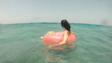 바다의 물결: 여자가 바다에서 부풀어올릴 수 있는 반지 위에서 헤엄친다.