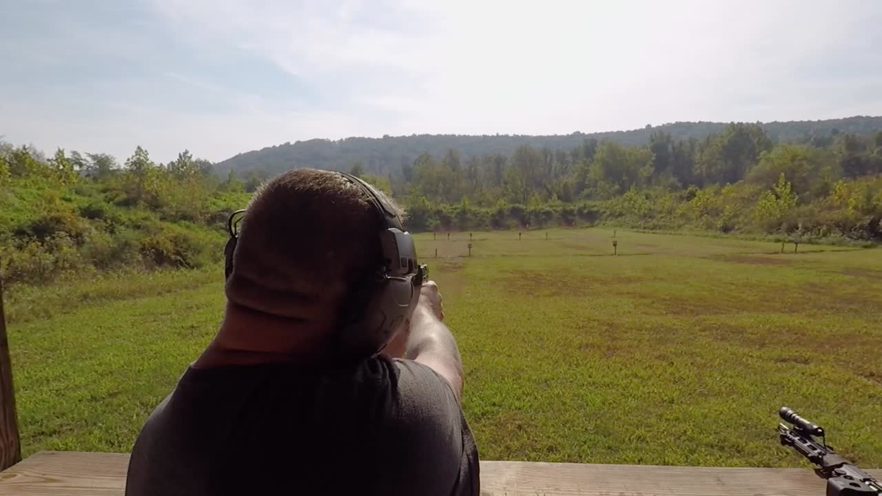 Rear View Adult Male Shooting Pistol Hand Gun on Shooting Range Shells Flying