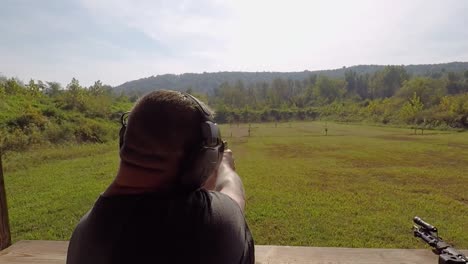 rear view adult male shooting pistol hand gun on shooting range shells flying