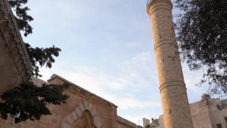 mardin's famous latifiye mosque's beautiful entrance from its garden on a sunny day, bottom up frame of the structure and it's minaret