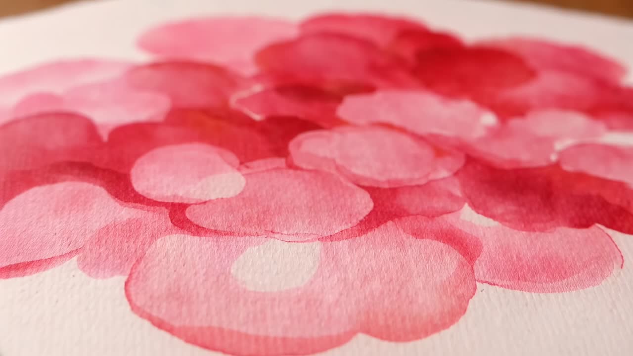 Camera in movimento che rivela strati di pittura rosa e rossa su carta ruvida su un tavolo da disegno, mettendo in risalto le sfumature del colore
