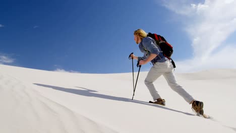 man with hiking pole walking on the sand dunes 4k