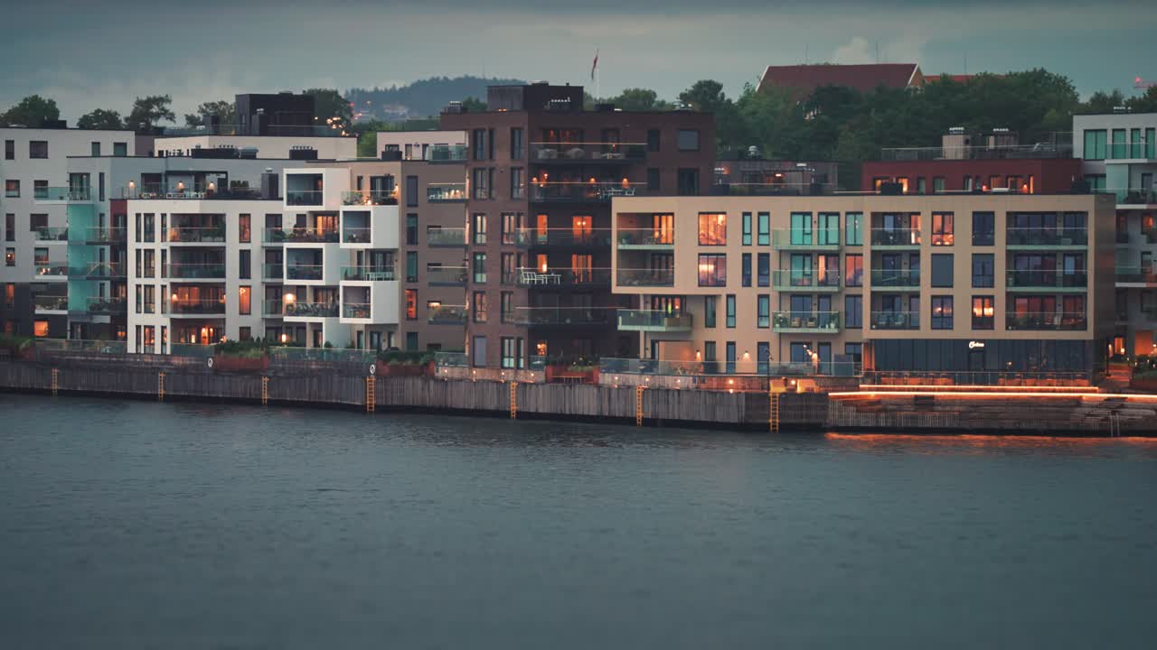 크리스티안샌드 시의 해안 구역에 있는 밝은 불빛으로 조명된 창문이 있는 현대적인 주거 건물