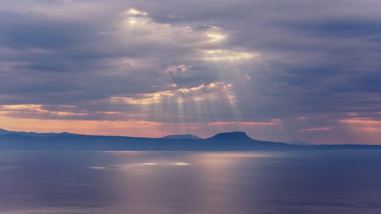 Vista aerea con drone di drammatici raggi di sole che filtrano tra le nuvole sopra il mare calmo, Creta, Grecia