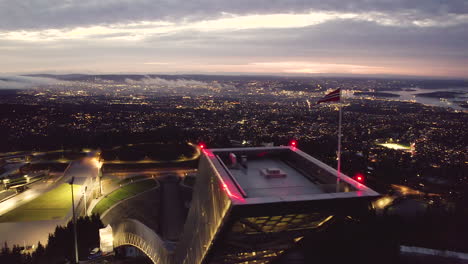 flag waving in the wind at the tower of holmenkollbakken at night in oslo, norway