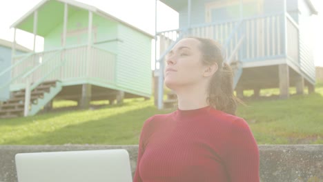 Junge-Frau-öffnet-Ihren-Laptop-Und-Atmet-Die-Frische-Luft-Mit-Linseneffekt-Am-Strand-Ein