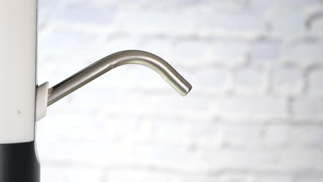 closeup of a hand filling a glass of water from a water dispenser