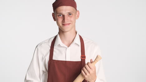 young baker in uniform holding rolling pin