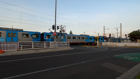 Train-travelling-past-a-level-crossing-with-boom-gates-down-and-red-lights-flashing