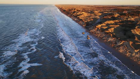 aerial view north sea water washes the beach with high dunes on a cold winter's evening when the sun is setting