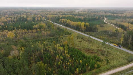 Aufnahme-Einer-Luftaufnahme-Des-Herbstwaldes,-Gelbe-Blätter-An-Bäumen,-Idyllische-Naturszene-Mit-Fallendem-Laub,-Herbstmorgen,-Autobahn-Mit-Autos,-Weiträumige-Drohnenaufnahme,-Die-Sich-Vorwärts-Bewegt