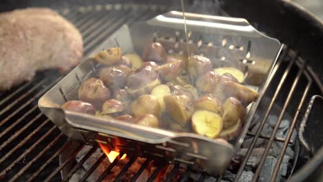 Chef-Rociando-Aceite-De-Oliva-Sobre-Papas-En-Una-Parrilla-Caliente-Con-Carne-De-Cerdo,-Cámara-Lenta