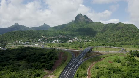 Vuelo-Aéreo-Hacia-Adelante-Sobre-El-Paisaje-Verde-De-Mauricio-Con-Puentes-De-Carretera-Y-Montañas-En-Segundo-Plano