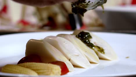 close up pouring pesto sauce in slow motion on top of some vegetables in a dish