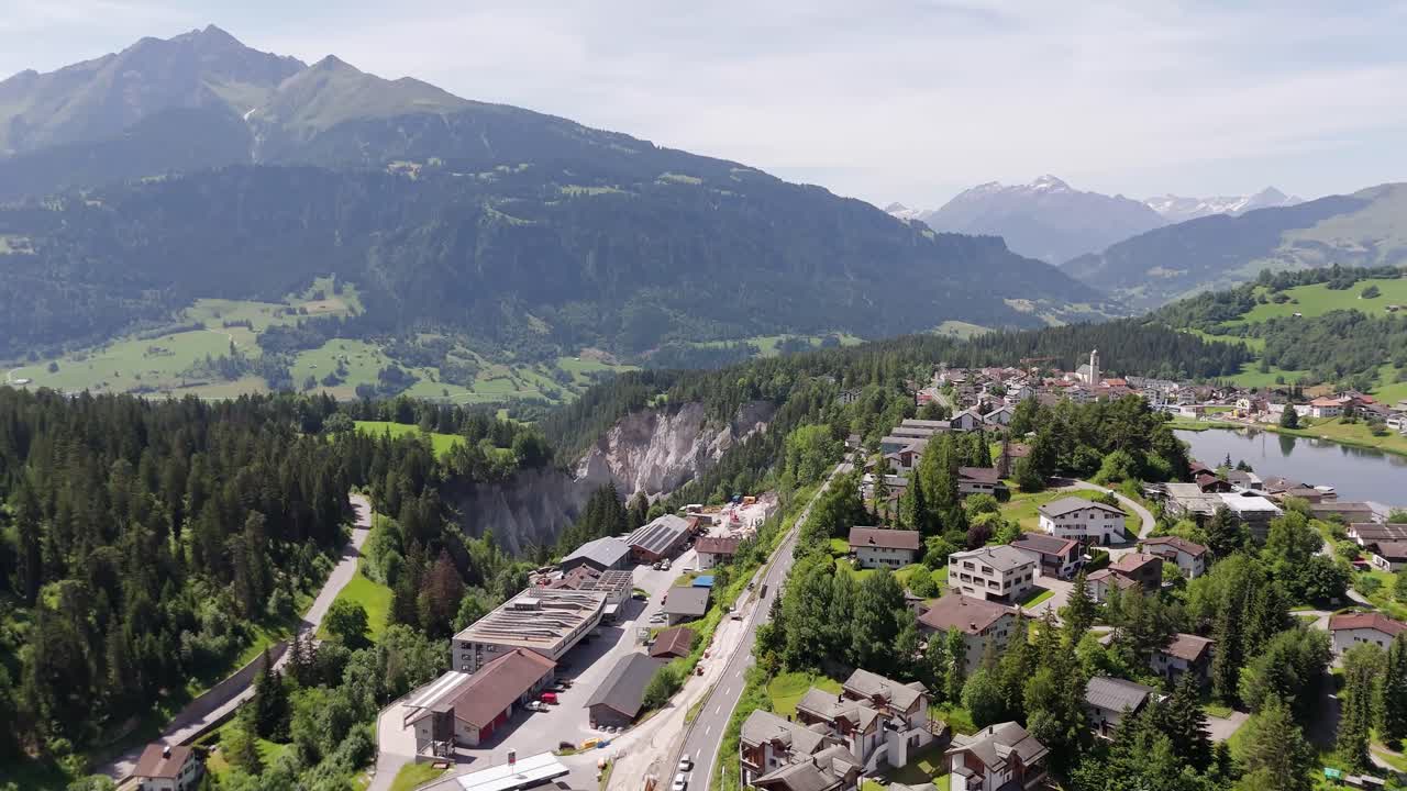 Magnificent small town in Switzerland with houses and homes along street. Laax located on top of mountains. Sunny day in summer. Aerial wide shot