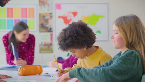 group of multi-cultural students putting hands up to answer question in classroom lesson